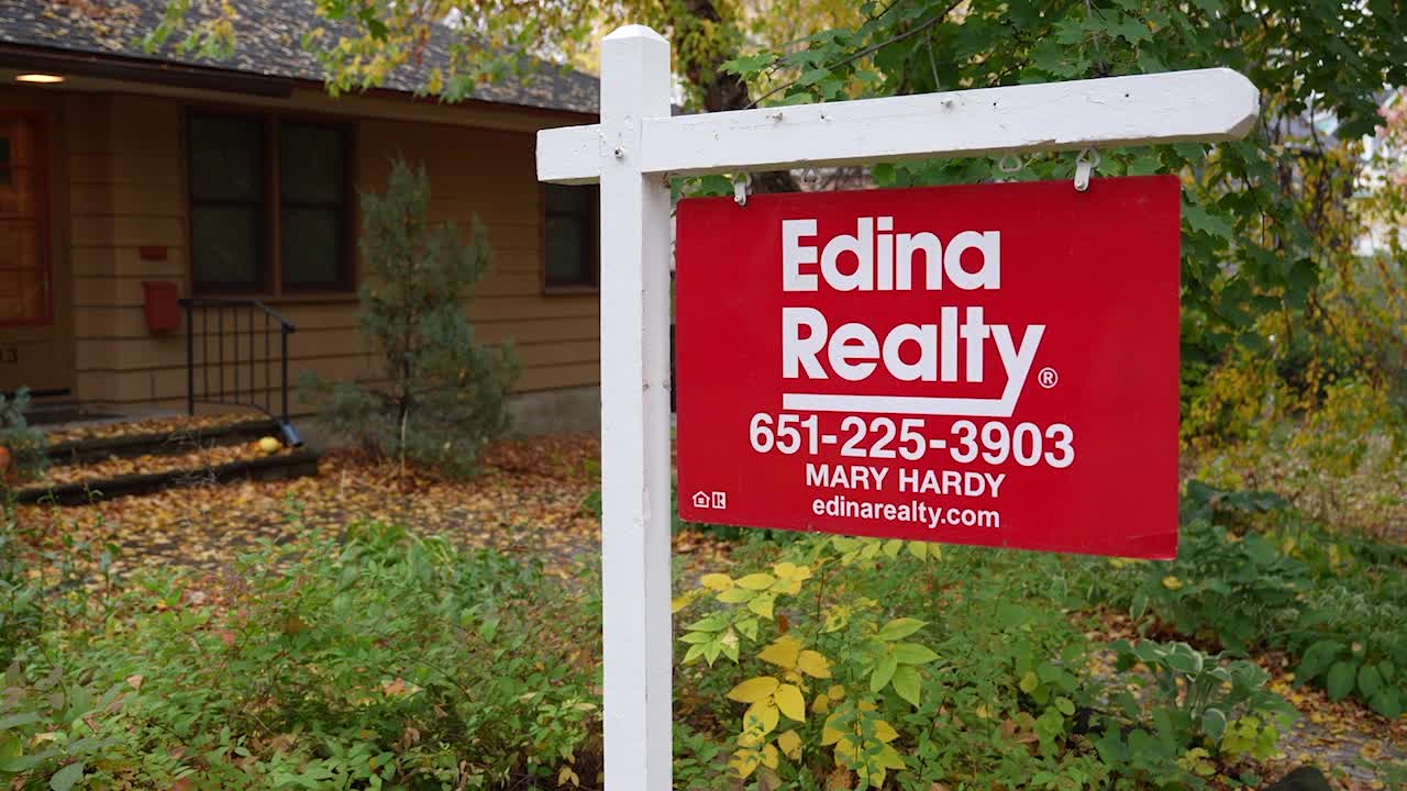 Young couple smiling, holding keys to their first home, symbolizing achievement amidst challenges.